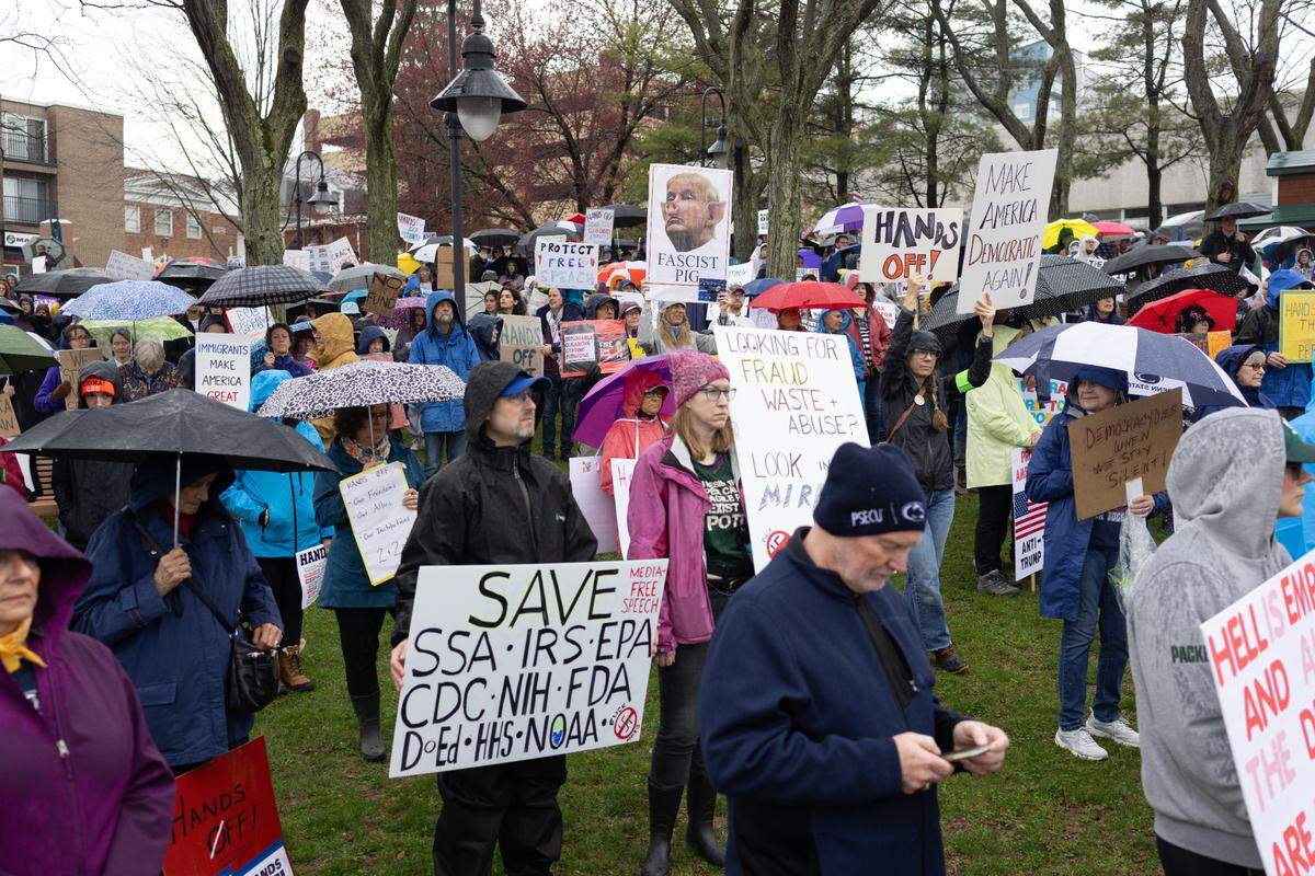 Protesters hold signs and umbrellas Saturday while listening to speakers at the “Hands Off!” rally at State College’s Sidney Friedman Park, in opposition of President Donald Trump. The event was part of a nationwide effort that saw more than 1,000 similar rallies held across all 50 states.