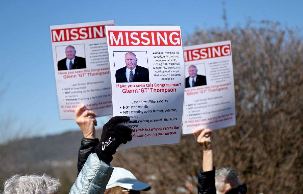 Peaceful protesters hold up signs about U.S. Rep Glenn “GT” Thompson’s as they gathered outside of his office in Bellefonte on Tuesday, March 18, 2025.