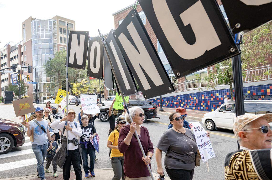 A group of protesters carried a No Kings sign as they marched through downtown for the No Kings anti-Trump rally on Saturday, Oct. 18, 2025. 