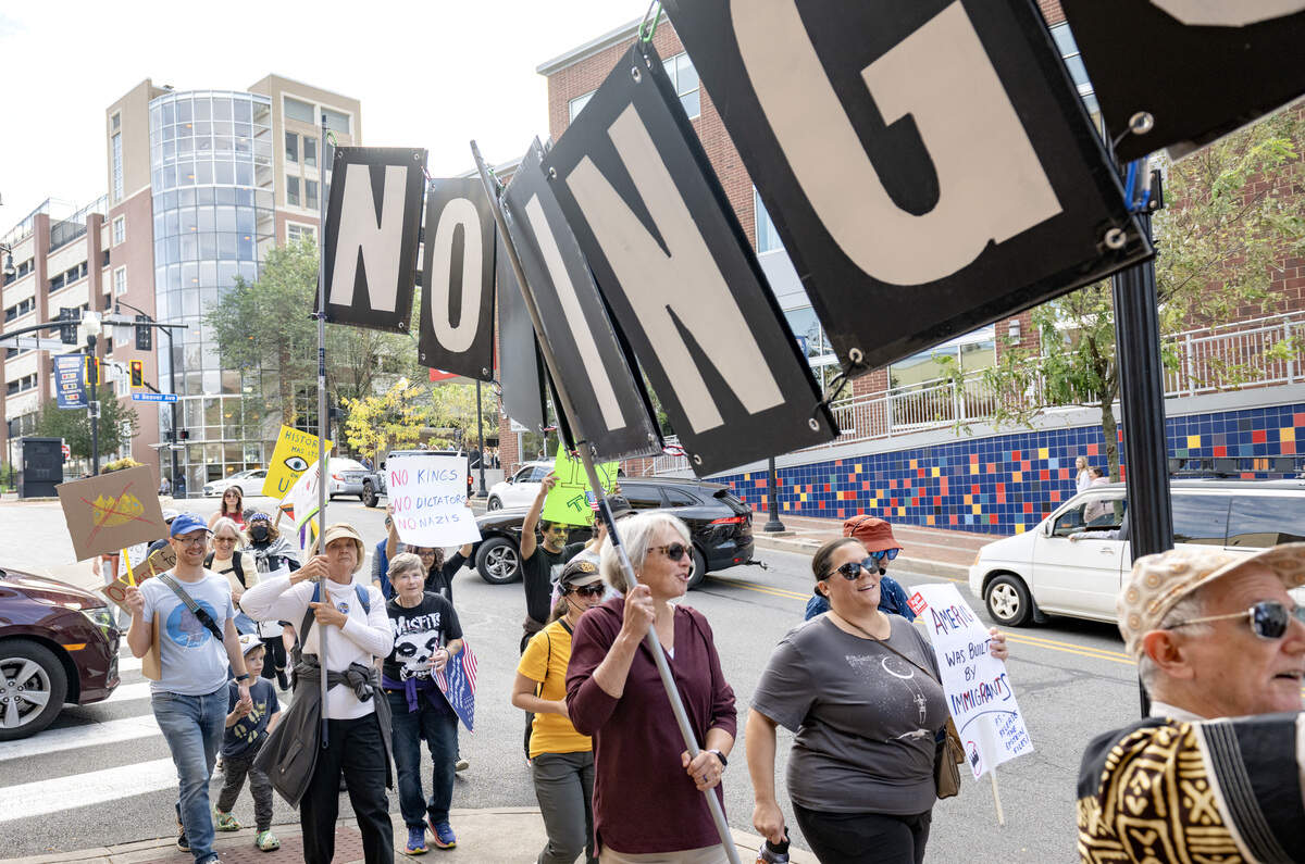 A group of protesters carried a No Kings sign as they marched through downtown for the No Kings anti-Trump rally on Saturday, Oct. 18, 2025.