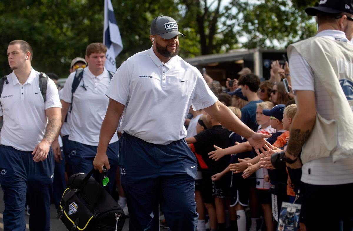 Penn State defensive tackle PJ Mustipher high fives fans as the team arrives at Beaver Stadium for the home opener against Ohio on Saturday, Sept. 10, 2022.