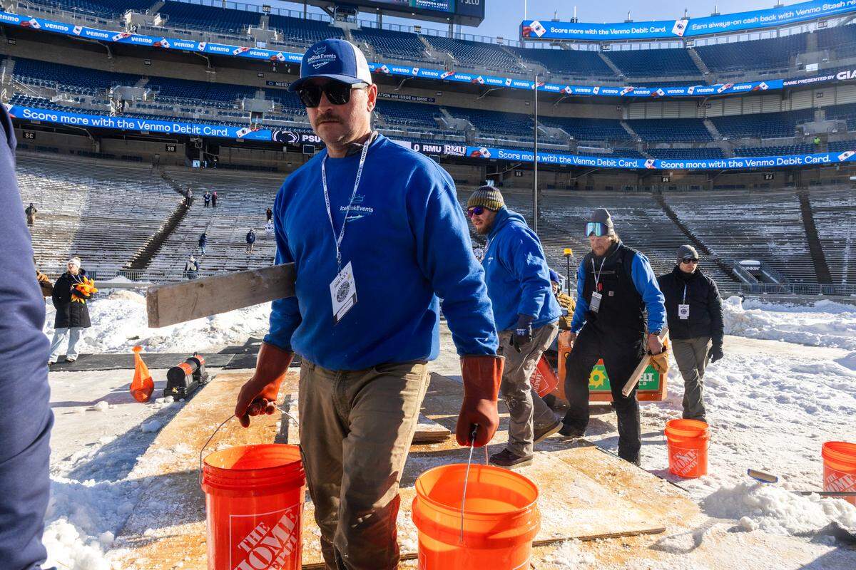 The ice maintenance crew carries buckets of water to the rink to conduct maintenance during the Penn State women’s hockey game at Beaver Stadium on Friday, Jan. 30, 2026.