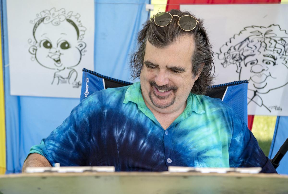 Artists Chip Mock smiles as he works on a caricature on June 28.