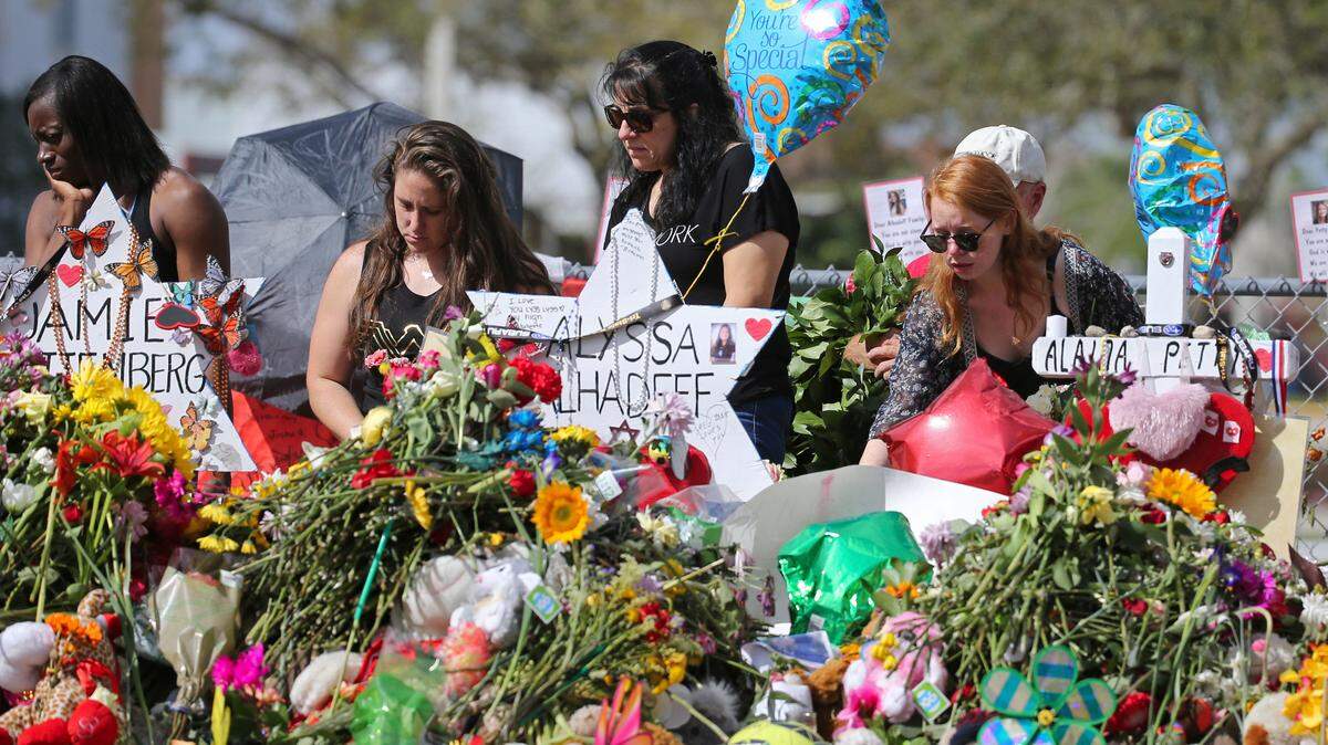 Mourners bring flowers as they pay tribute at a memorial for the victims of the shooting at Marjory Stoneman Douglas High School on Sunday, Feb. 25, 2018, in Parkland, Fla.