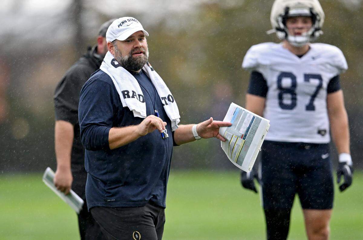 Penn State offensive coordinator Andy Kotelnicki talks to player before they run a play during practice in the rain on Wednesday, Sept. 24, 2025.  