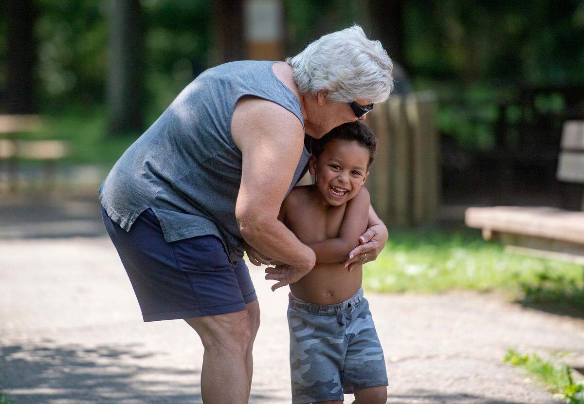 Amy Mitchell hugs her 3-year-old grandson as he giggles after running to her arms.  Mitchell has guardianship of her grandson who had been running around the park and wading into the creek.