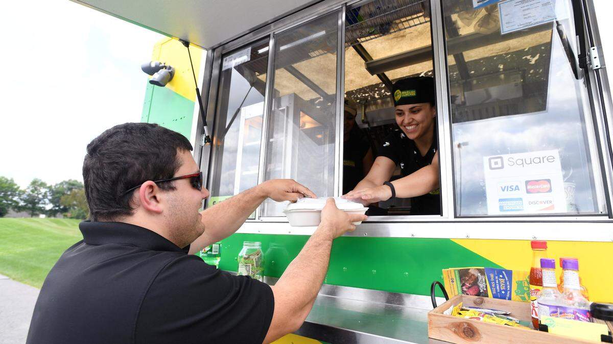 Yama Castilho hands Brent Smith his order from the Brazilian Munchies food truck on Monday at AccuWeather in State College.