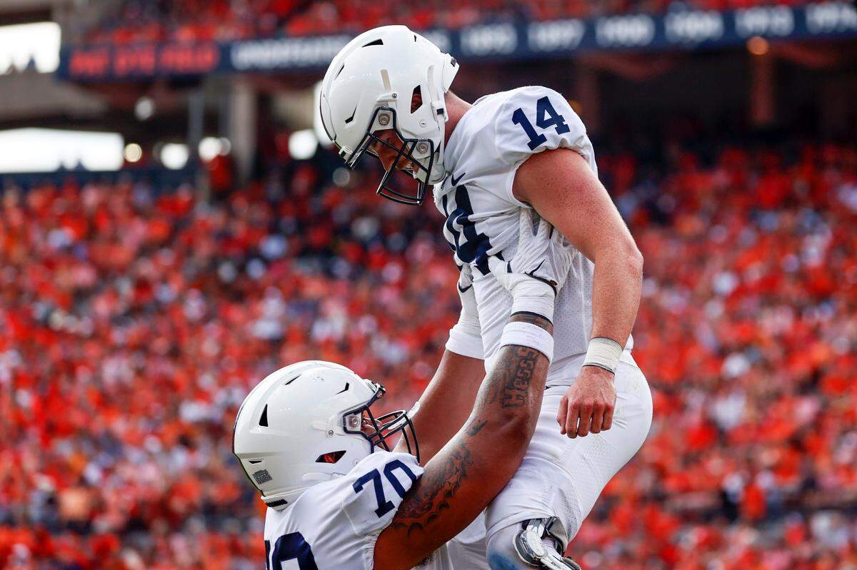 Penn State offensive lineman Juice Scruggs (70) celebrates with Penn State quarterback Sean Clifford (14) after he scored a touchdown against Auburn during the first half of an NCAA college football game, Saturday, Sept. 17, 2022, in Auburn, Ala. (AP Photo/Butch Dill)