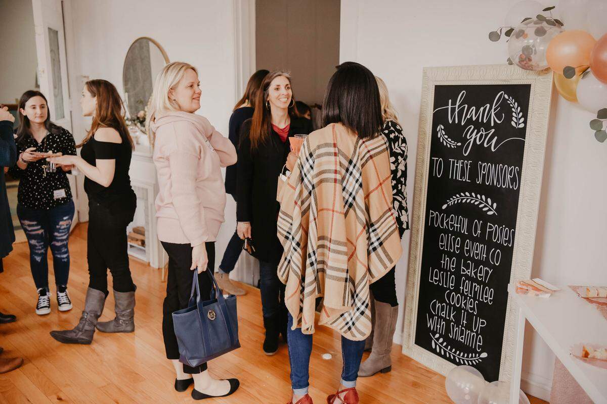 Local creatives and business owners chat next to a sign thanking the sponsors of the girl gang meet-up event on Feb. 24, 2019.