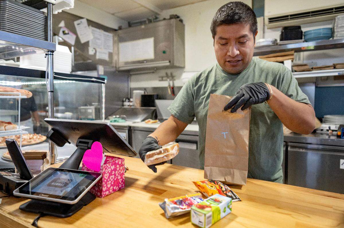 Lucio Perez, owner for Little Mammas in Pleasant Gap, bags up a lunch bag for youth on Tuesday, June 11, 2024. The free lunches include a sandwich, fruit or chips and a juice or water.