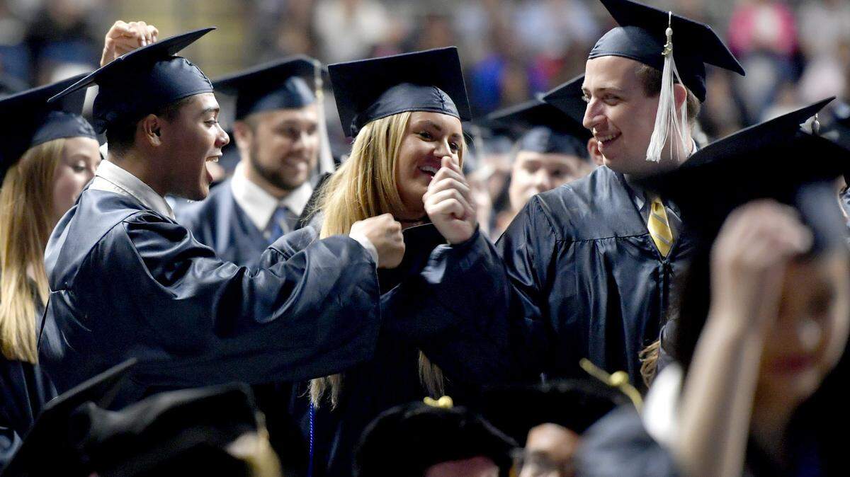 Friends fist bump after being named graduates and turning their tassels during a past Penn State commencement ceremony. 2020 grads will be able to celebrate their graduation with special commencement ceremonies in 2022.