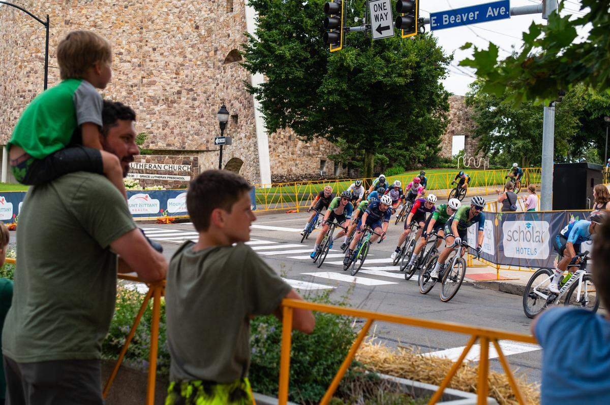 Participants in the Men’s Cat 1 and Cat 2 cycling race go around a corner while the crowd watches during the State College Criterium on Saturday, July 26, 2025 in State College, Pa.