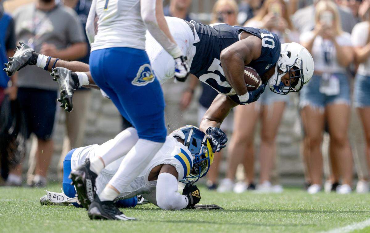 Penn State running back Nick Singleton dives over a Delaware defender during the game on Saturday, Sept. 9, 2023.
