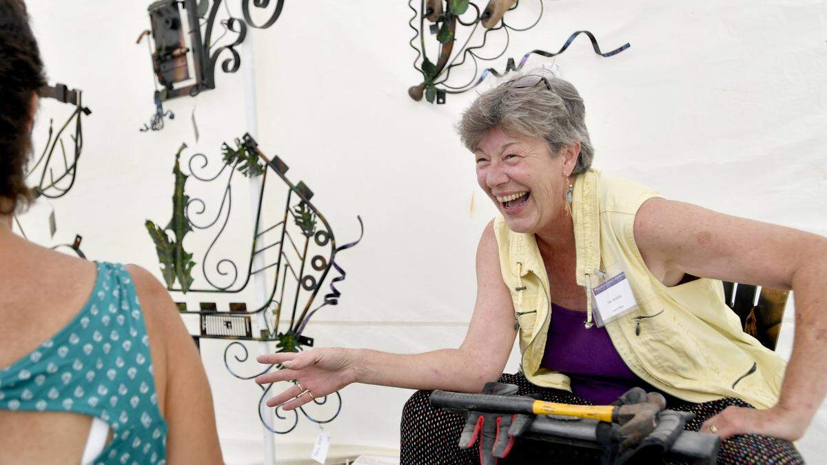 Kay Jaramillo laughs with a costumer in her booth at the People's Choice Festival in July 2017.