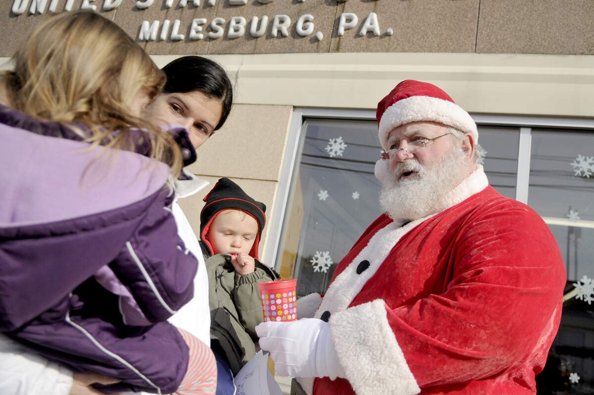 Dressed as Santa, Michael McCartney chats with Madison Stamm, 3, Mandi Stamm and Blake Stamm, 1, outside of the MIlesburg post office during the Milesburg "Home Town" Christmas in 2013.