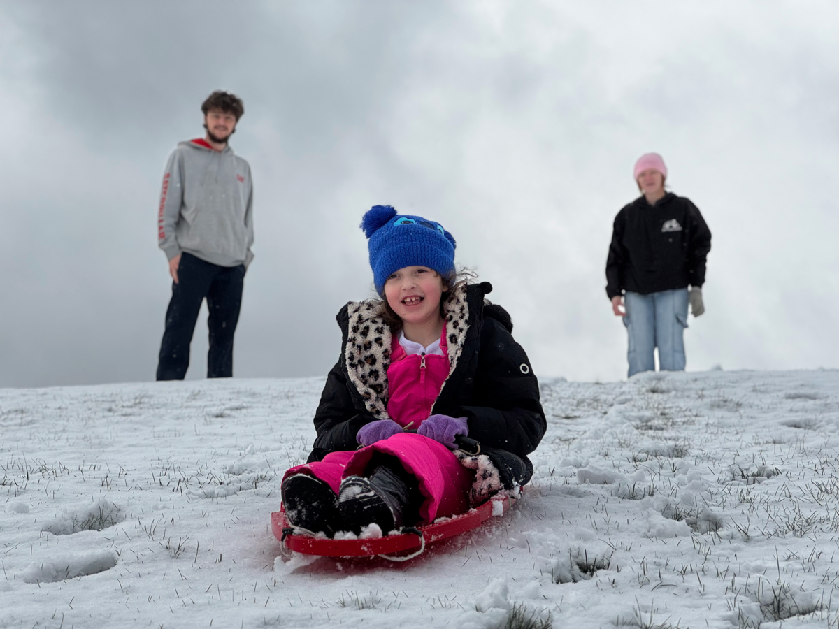 Averie Hopkins sleds down a hill at Cold Stream Dam in Philipsburg as her uncle, Eli Hopkins, and mother, Savannah Hopkins, watch on Dec. 2, 2025.