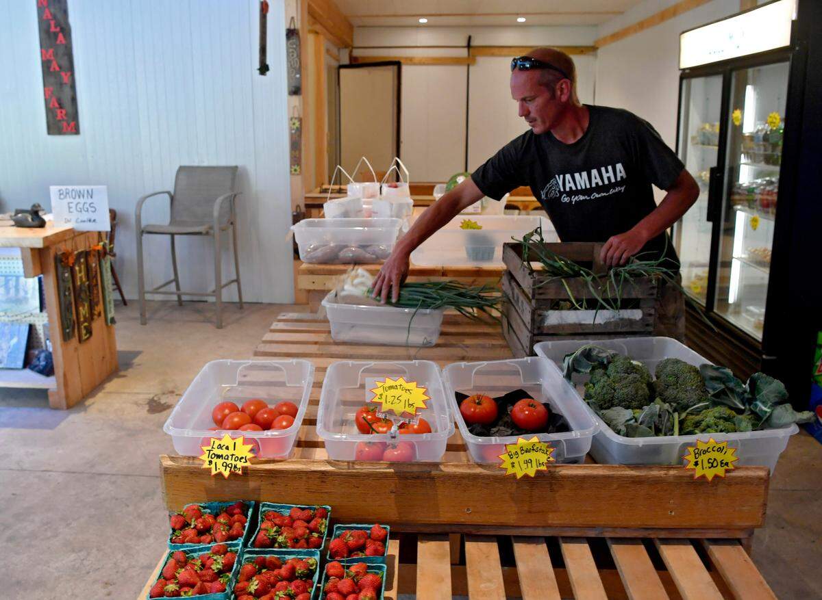 Ojay Guenot restocks local produce Monday at Nala May Farm and Nursery in Karthaus.