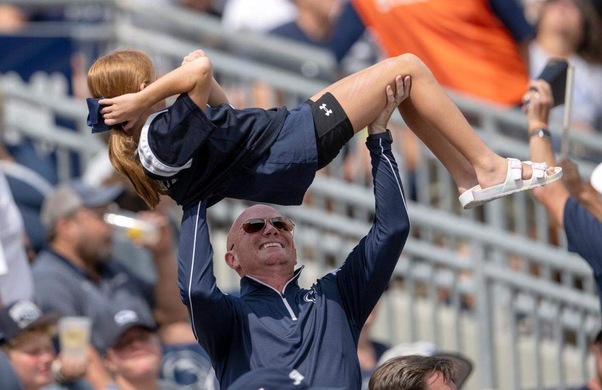 A Penn State fan lifts a girl over his head to celebrate the touchdown during the game against Delaware on Saturday, Sept. 9, 2023.