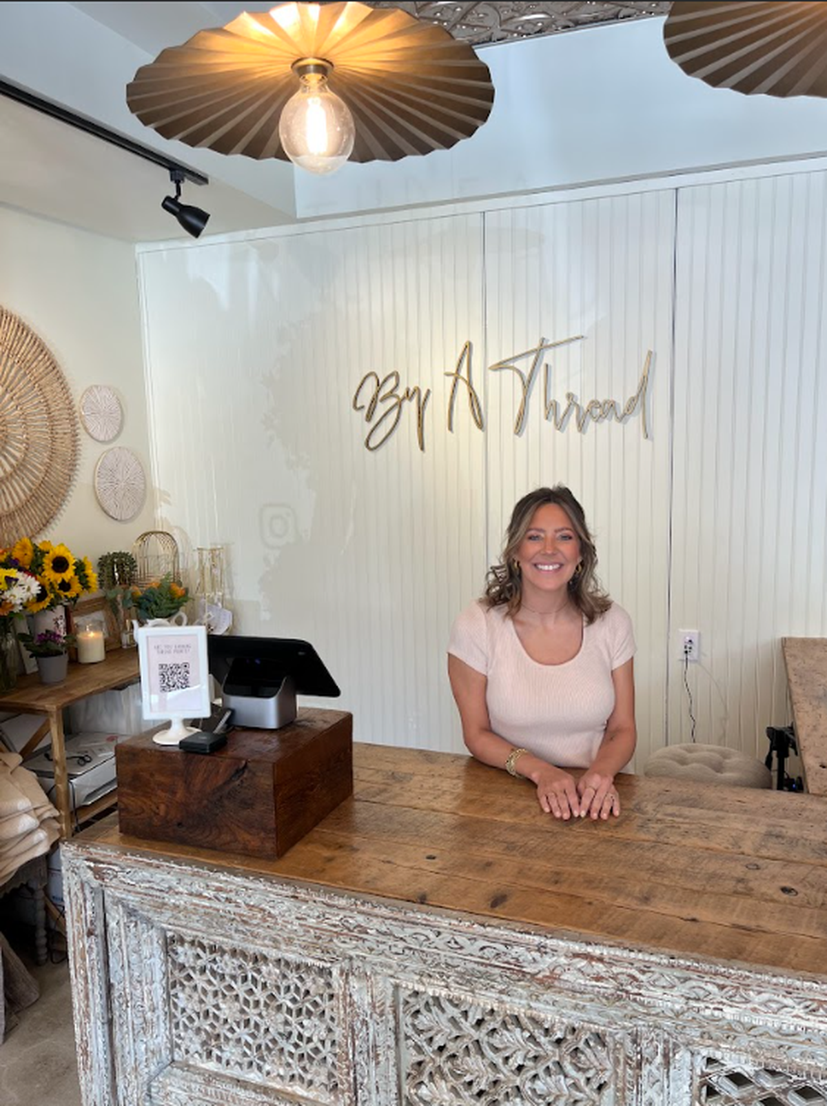 By A Thread Boutique owner Emily Boone sits behind the counter at her State College shop in this 2024 photo.