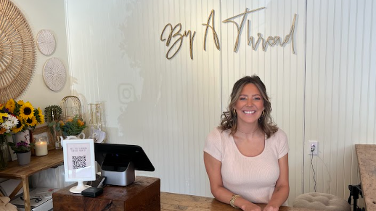 By A Thread Boutique owner Emily Boone behind the counter at her boutique’s new location.