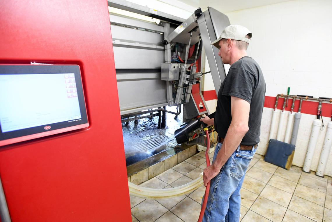Adam Coursen sprays down the area where the cows are milked via the robotic milking system in June 2018 at Valley Wide Farm in Spring Mills.