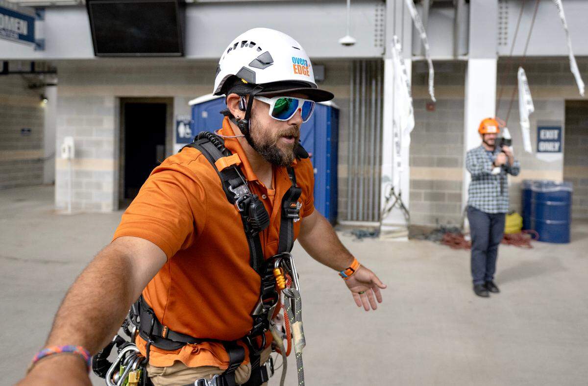 After being hooked in on the ropes and the harness is double checked, participants are told to stand up on the edge of the stadium.