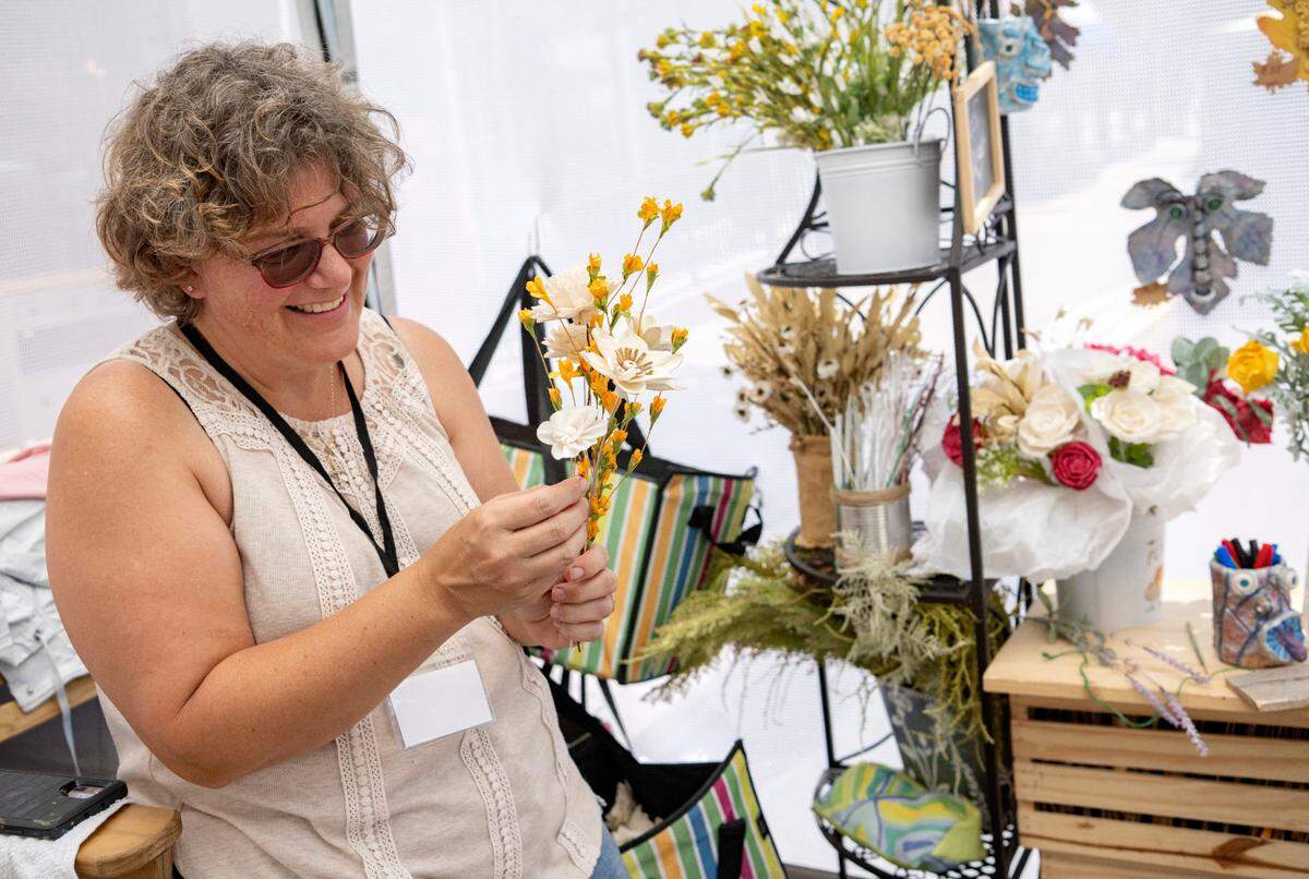 Amanda Robinson works on a bouquet of her hand painted wood flowers at the 39th Annual Bellefonte Arts and Crafts Fair on Friday, Aug. 5, 2022.