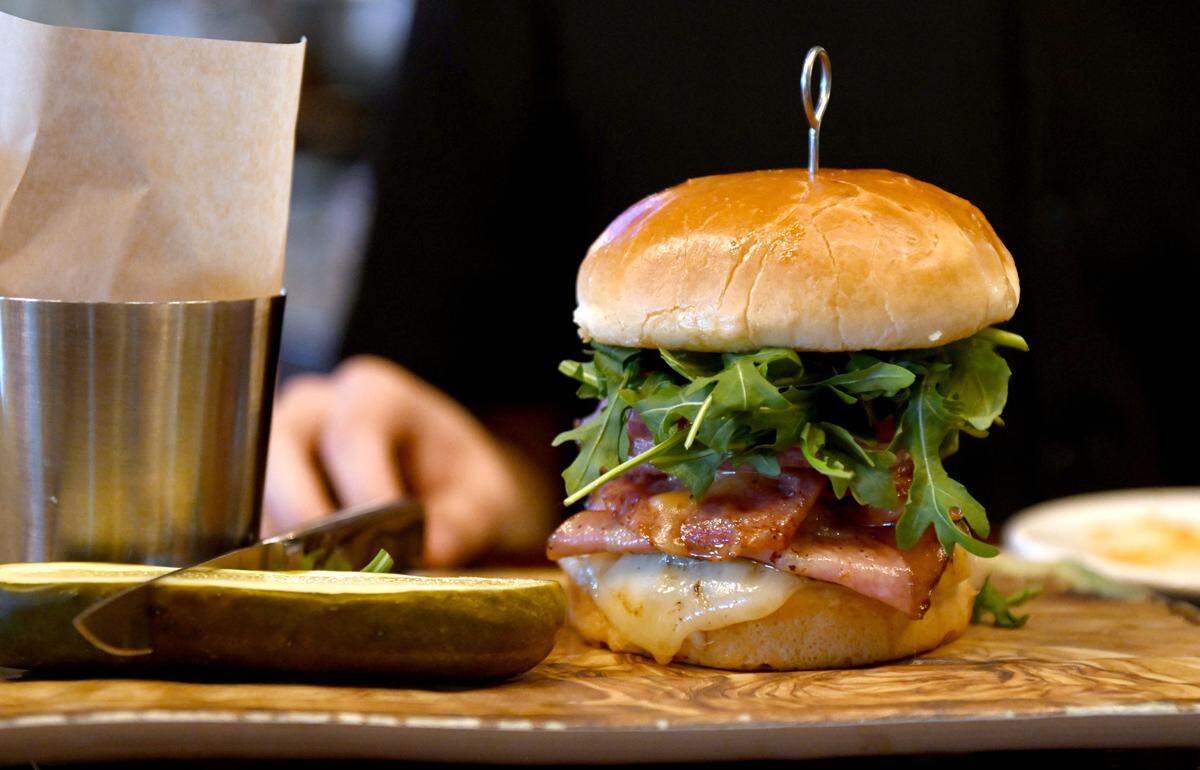 Centre Daily Times reporters wait to taste the Coach Campbell’s Roman Burger at The Field. The burger features salami, mortadella, white cheddar, arugula, tomato, onion, mayo and Italian dressing on a brioche roll.