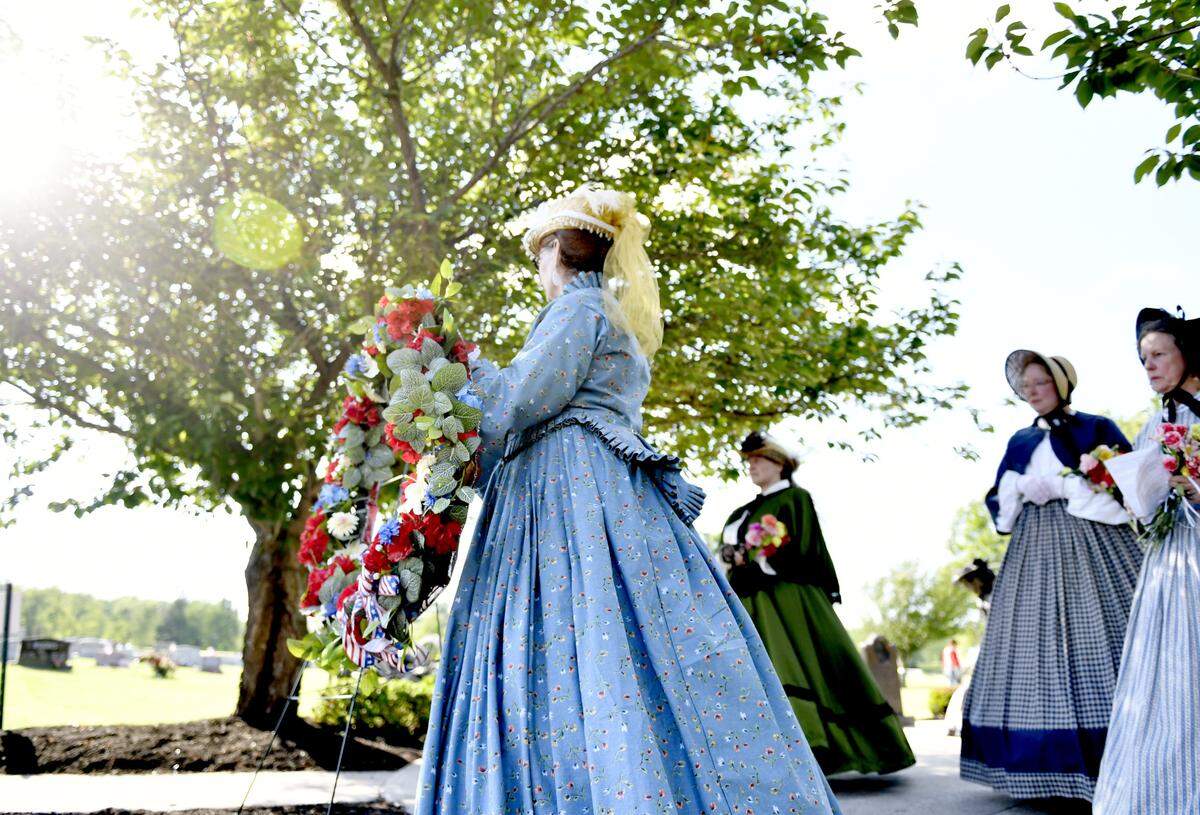 Women honoring Emma Hunter, Elizabeth Myers and Sophie Keller place a wreath at the cemetery at Zion Lutheran Church as part of the 153rd Memorial Day Service on May 29, 2017.