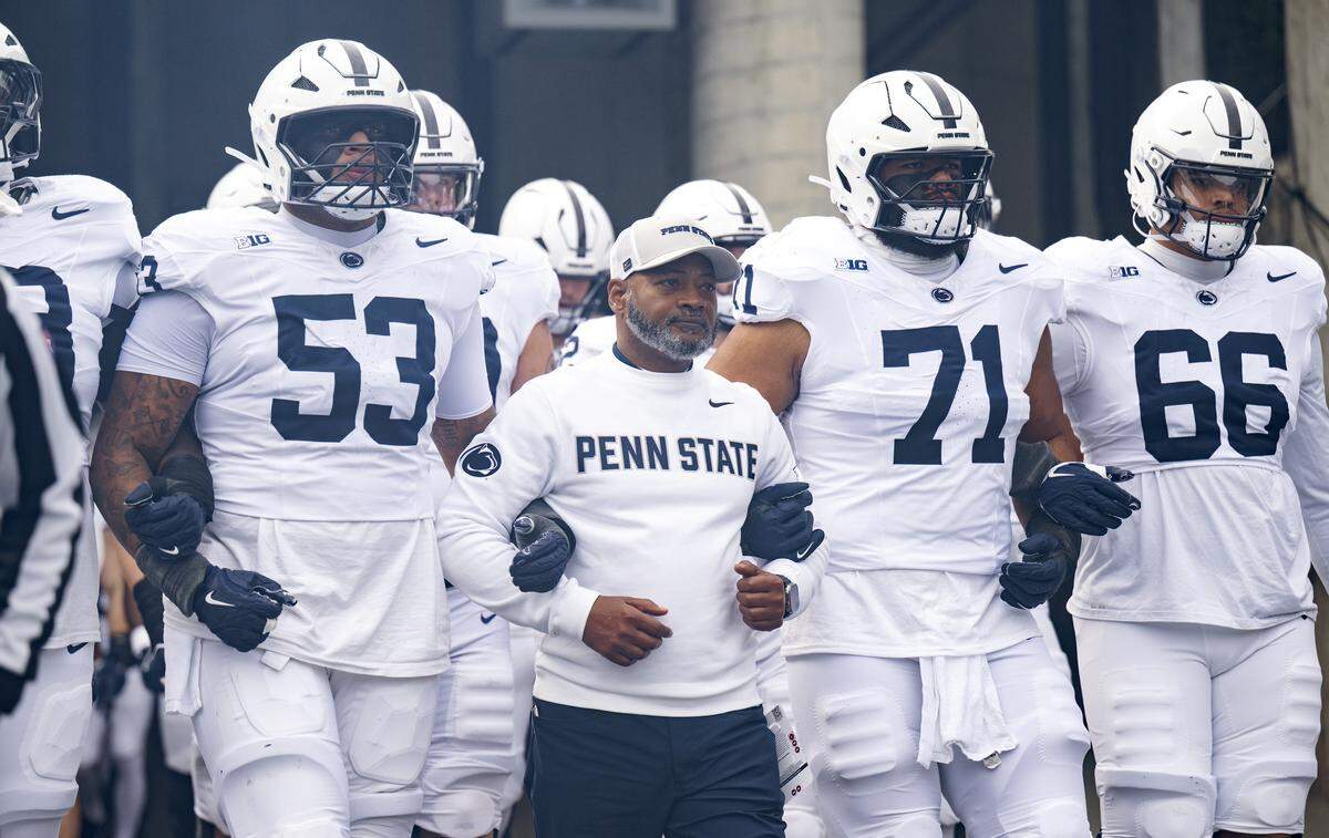 Penn State interim coach Terry Smith links arms with players as they walk onto the field for the game against Ohio State on Saturday, Nov. 1, 2025. 