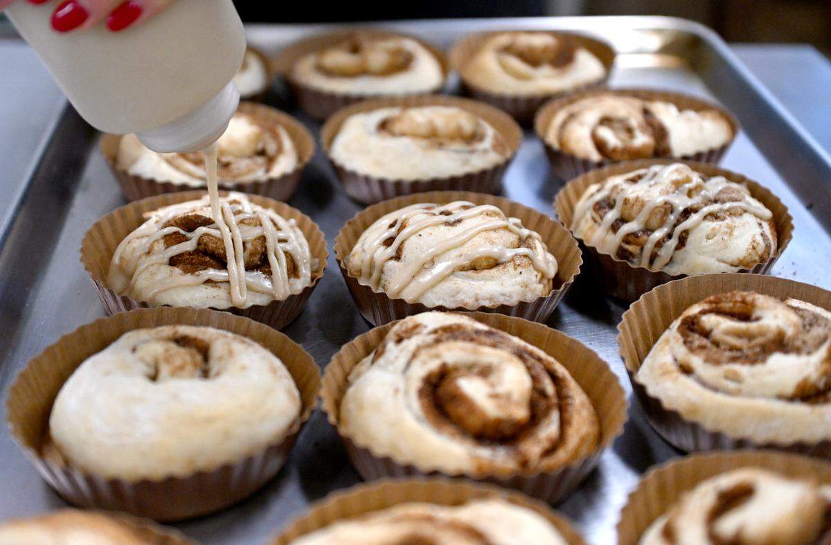 Paige Musser adds the frosting to a batch of cinnamon rolls at Kathryn’s.