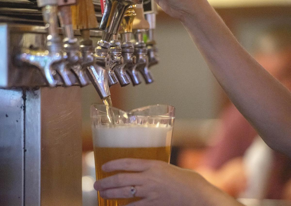 A bartender taps a beer at Bill Pickle’s Tap Room in July 2018.
