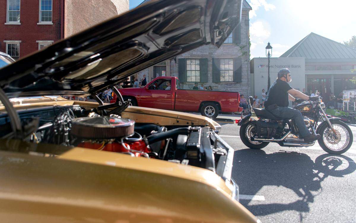 A car shows off it’s engine as a motorcycle cruises Allegheny Street for the Bellefonte Cruise on Friday, June 17, 2022.