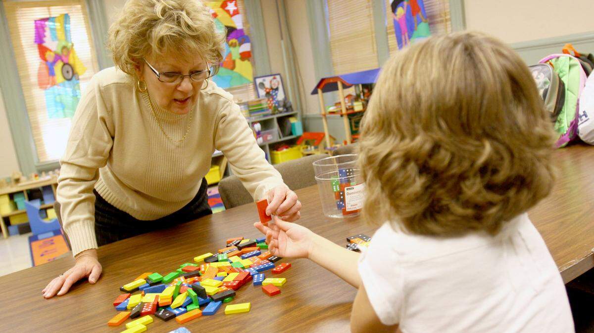 Vickey Warshaw plays a game of dominoes in 2010 with a child at the Centre County Child Access Center in Bellefonte.