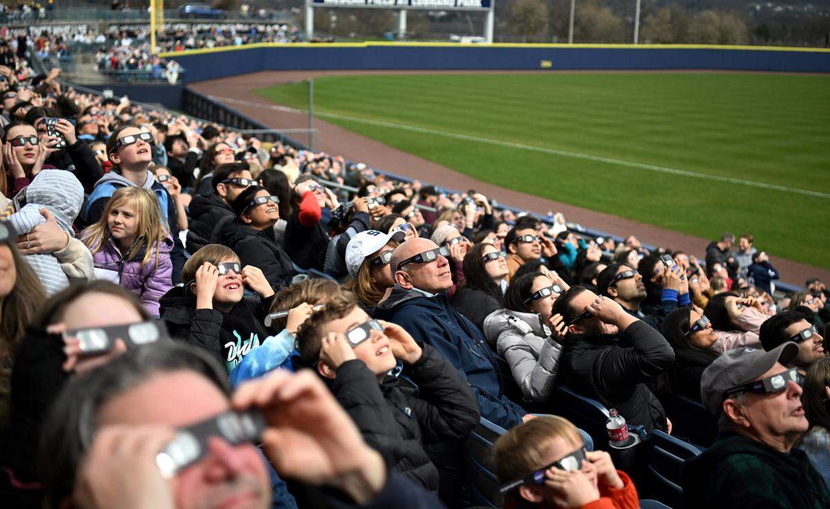 People look at up the sky to see a glimpse of the solar eclipse through the clouds during SolarFest on Monday at Medlar Field. SolarFest, hosted by Penn State’s Eberly College of Science and the State College Spikes, drew over 8,000 people.