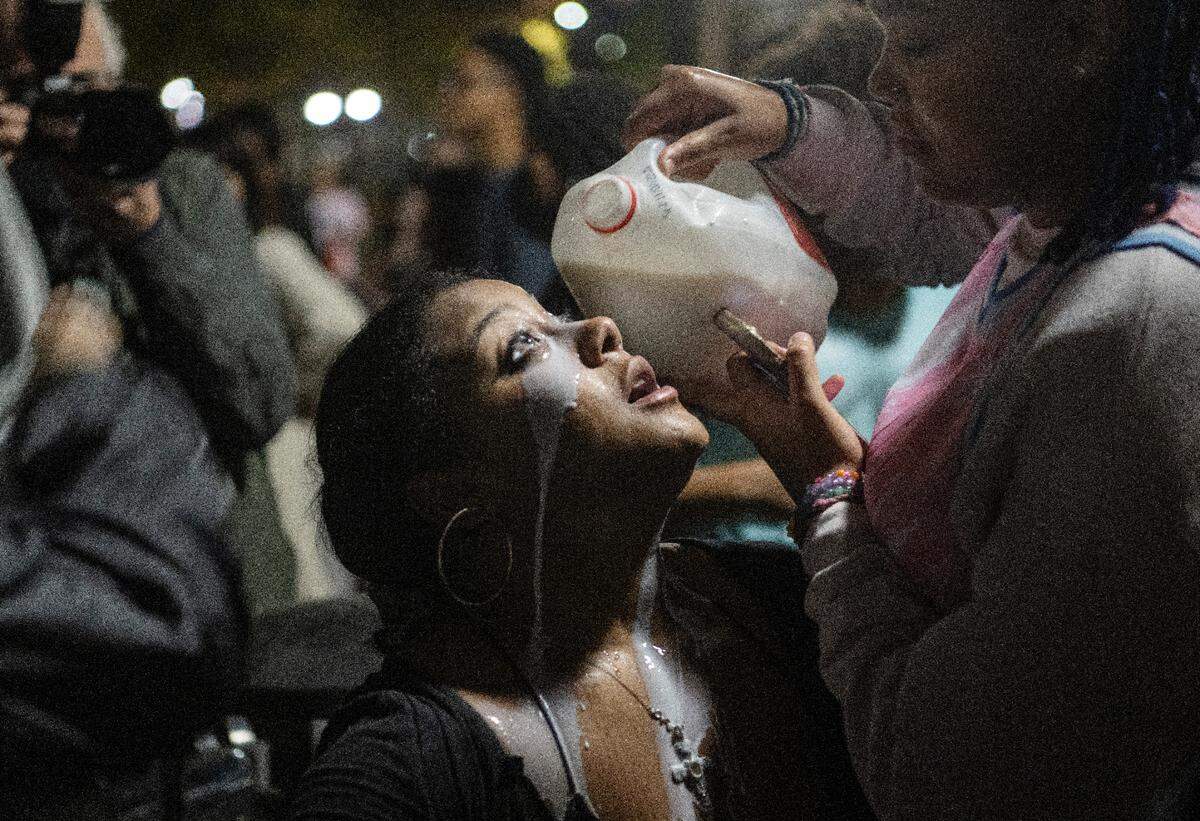 A woman has milk poured on her eyes after being hit with a bear deterrent spray outside of the Thomas Building on Monday, Oct. 24, 2022.
