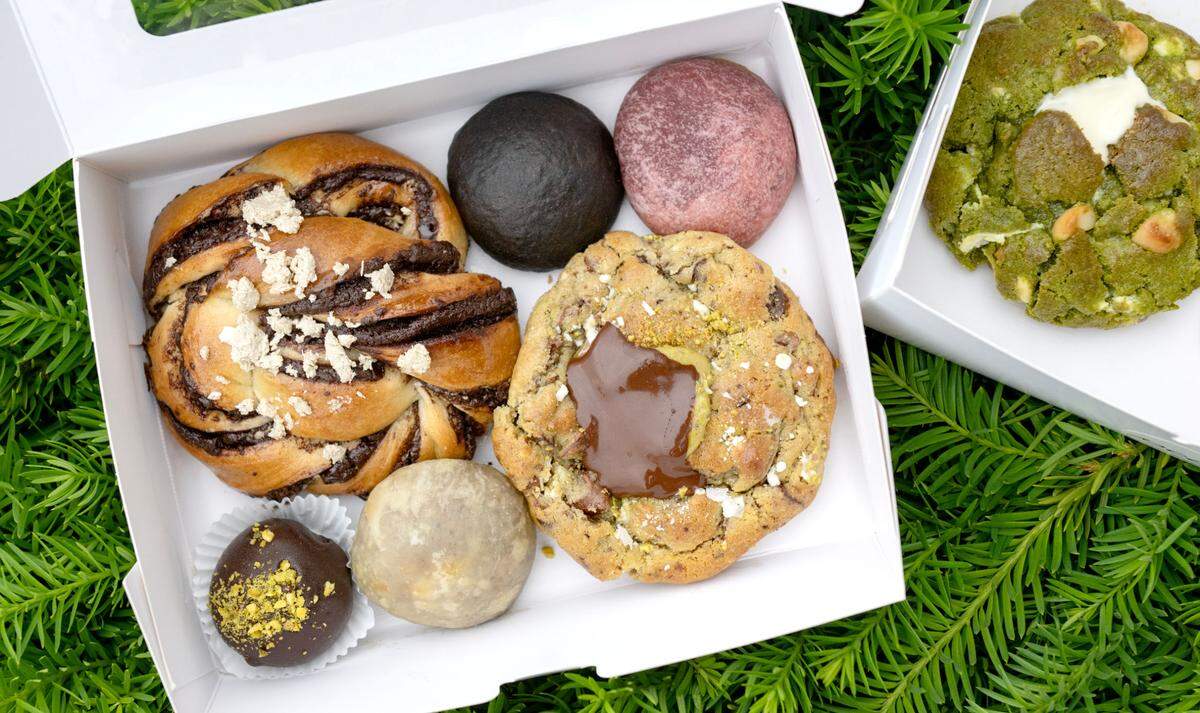 A variety of treats from Pouf Patisserie including a chocolate halva babka bun, a mocha noir bomb, a raspberry bomb, a Dubai truffle, a chocolate hazelnut bomb and a triple chocolate pistachio cookie.