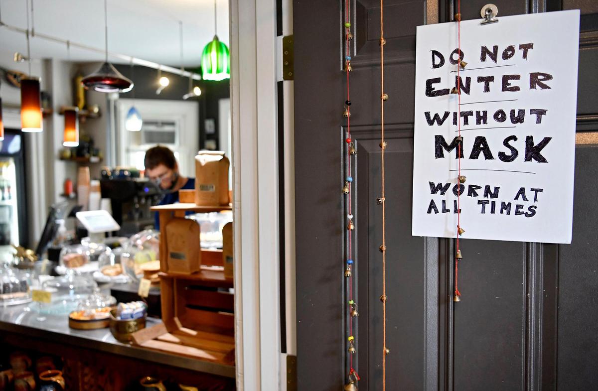 A sign on the door at Cafe Lemont reminds patrons they must wear a mask when inside to order and pick up.