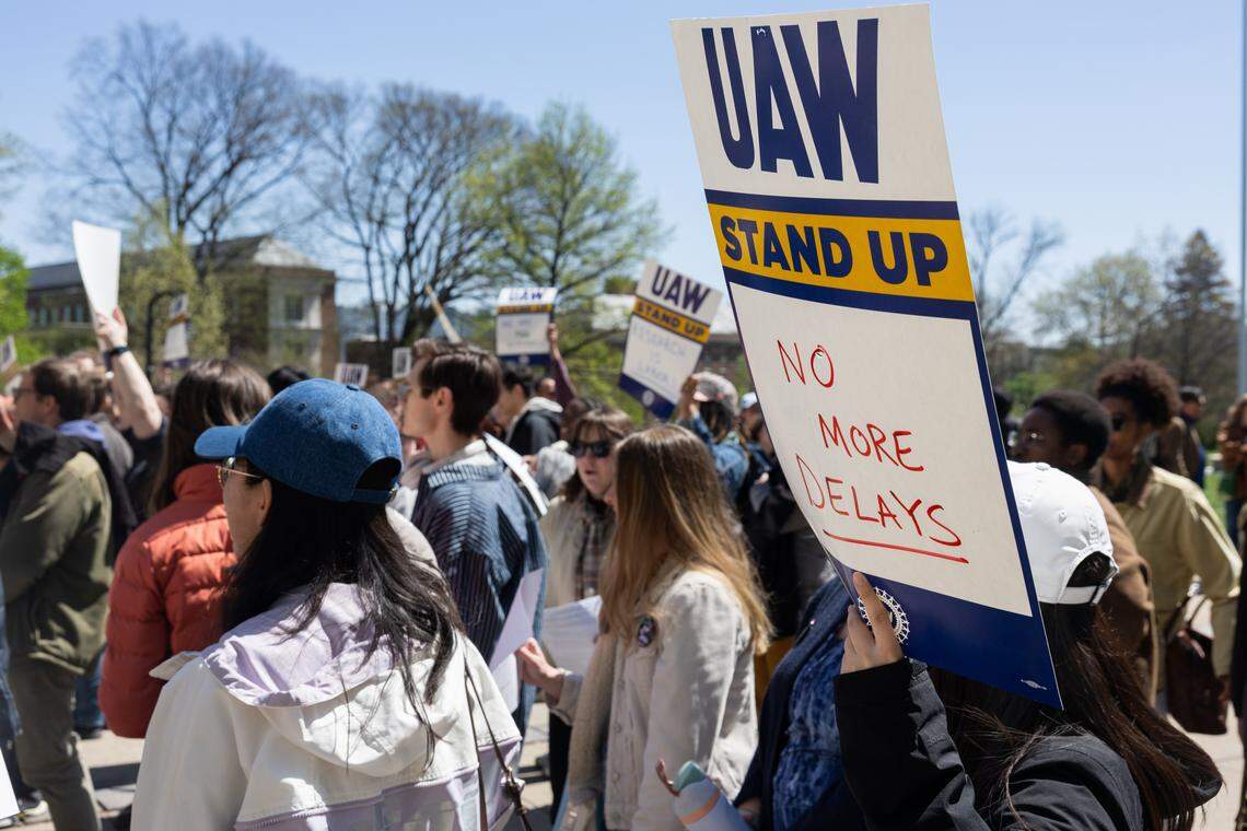 Graduate students hold up posters during a rally in front of Old Main on Tuesday, April 21, 2026.