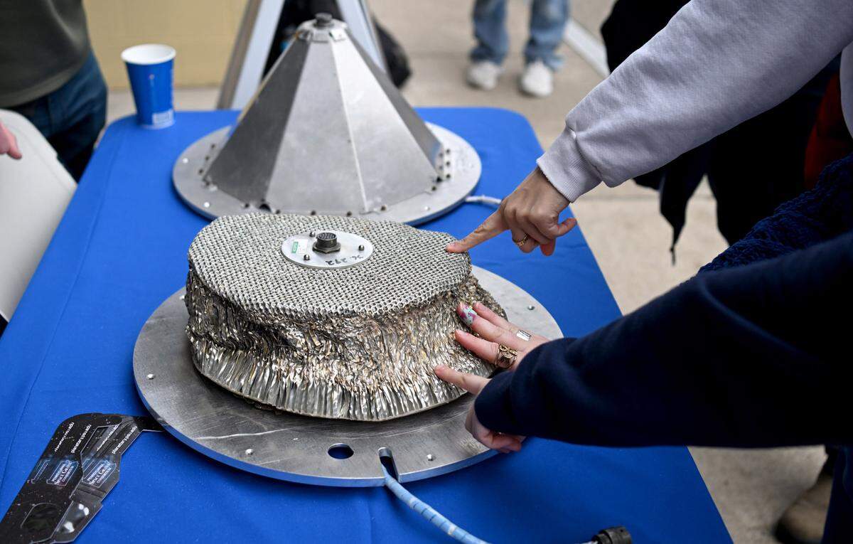 People touch shock absorbers from sounding rockets that landed on the moon, part of Monday’s SolarFest.