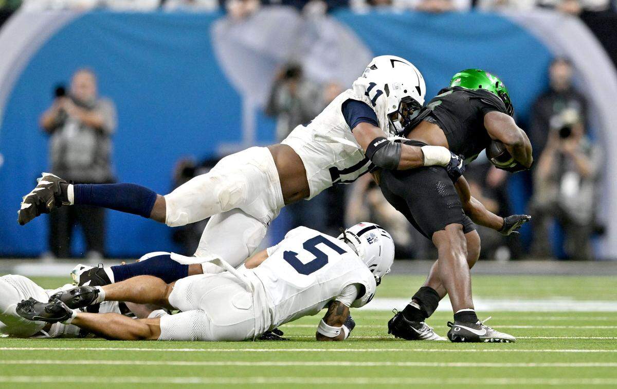 Penn State cornerback A.J. Harris and safety Zakee Wheatley stop Oregon’s Noah Whittington during the Big Ten Championship game at Lucas Oil Stadium on Saturday, Dec. 7, 2024.