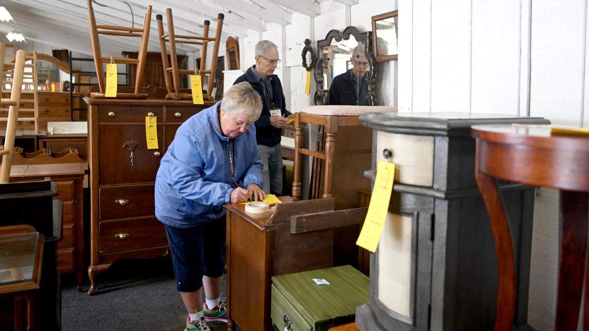 Joann McCormick works with Glen Blume as they label furniture and mirrors for the Foxdale Village semi-annual garage sale on Thursday, April 27, 2023. The sale will be on Saturday, April 29, 2023.