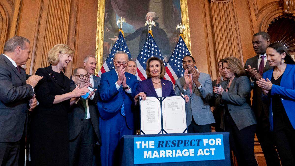 House Speaker Nancy Pelosi, accompanied by Senate Majority Leader Sen. Chuck Schumer and other members of Congress, signs the Respect for Marriage Act on Capitol Hill on Thursday.
