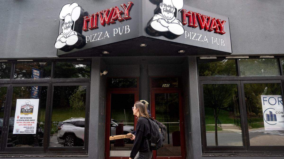 Pedestrians pass the former HiWay Pizza Pub at 340 E. College Ave. in downtown State College on Monday, Sept. 18, 2023. A sign in the window says to visit their location at 1301 W. College Ave.