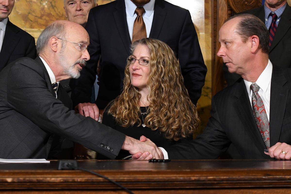 Pennsylvania Gov. Tom Wolf of Pennsylvania shakes hands with Jim Piazza after signing anti-hazing legislation inspired by Piazza’s son, Penn State student Tim Piazza who died after a night of drinking in a fraternity house, Friday, Oct. 19, 2018 in Harrisburg, Pa. Sitting between them is Evelyn Piazza, the mother of Tim Piazza. (AP Photo/Marc Levy)