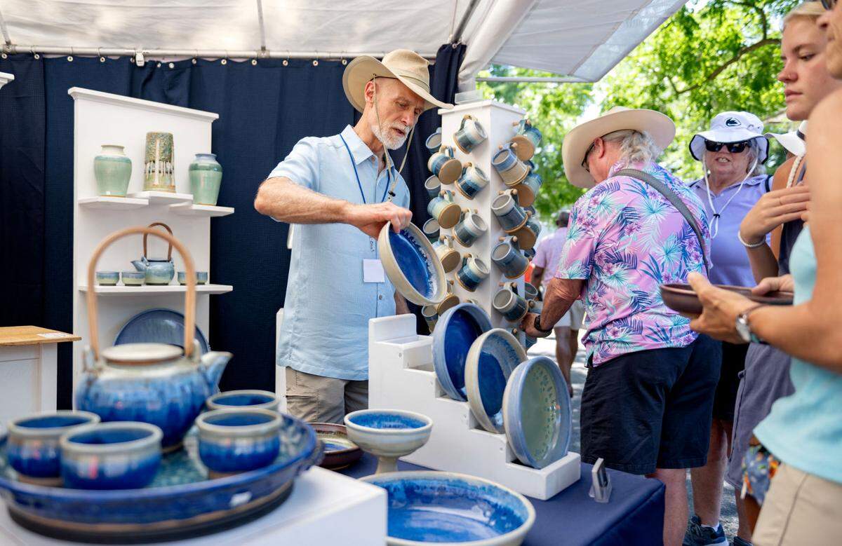 Tim Robinson encourages visitors to look at his pottery plates and mugs at his booth at the Central Pennsylvania Festival of the Arts on Friday, July 12, 2024.