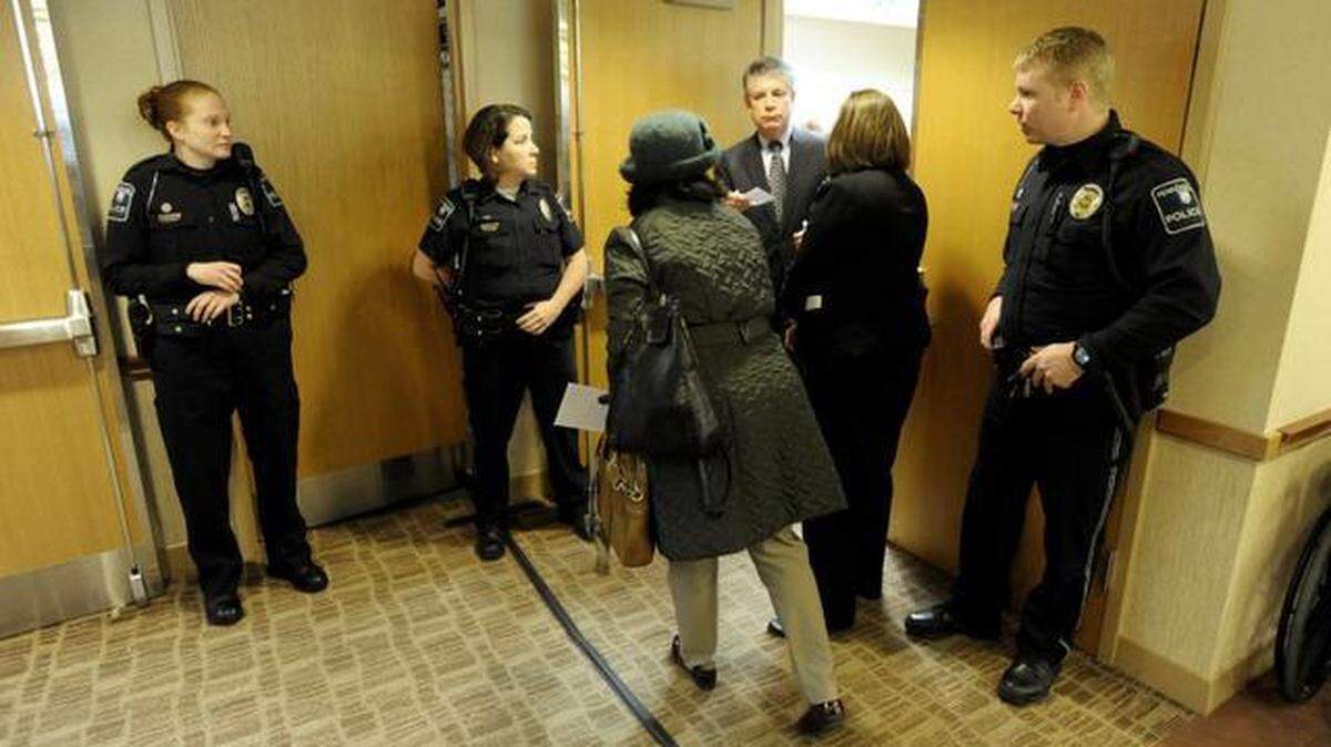 Above: Members of the public watch the public-comment period via video stream at the Board of Trustees meeting on Friday at the Penn Stater Conference Center Hotel. Left: Police stand outside of a meeting room during the meeting. 
