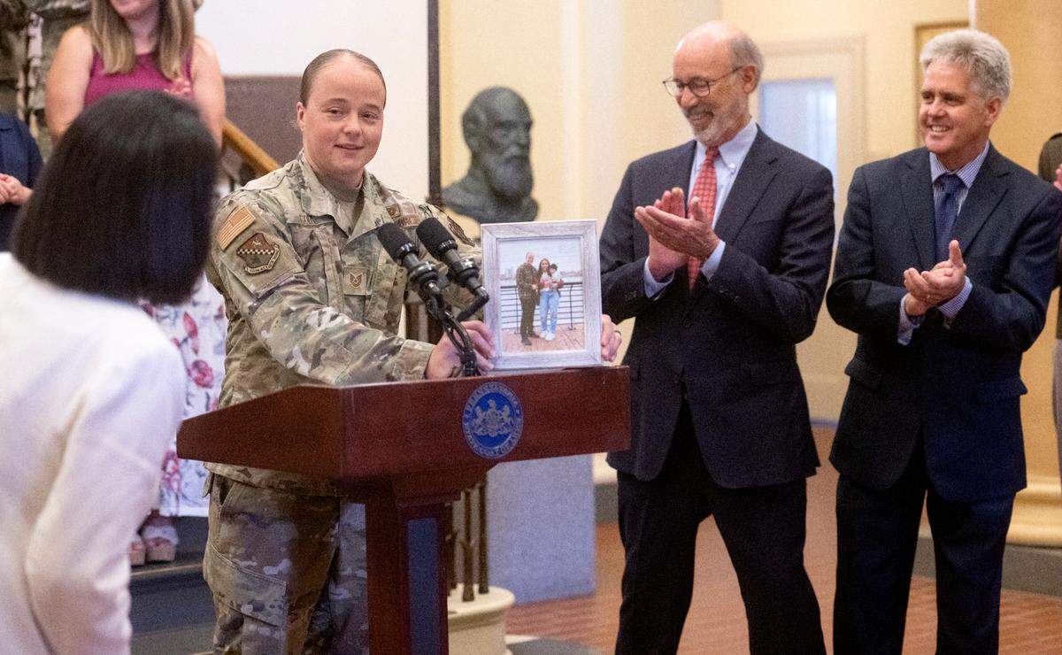 Tech. Sgt. Chelsea Coia of the PA Air National Guard shows a family photo Tuesday as she shares the impact the Military Family Education Program has had on her family during a celebration of the bill at Penn State’s Old Main. Coia will graduate from Penn State world campus this summer thanks to the bill.