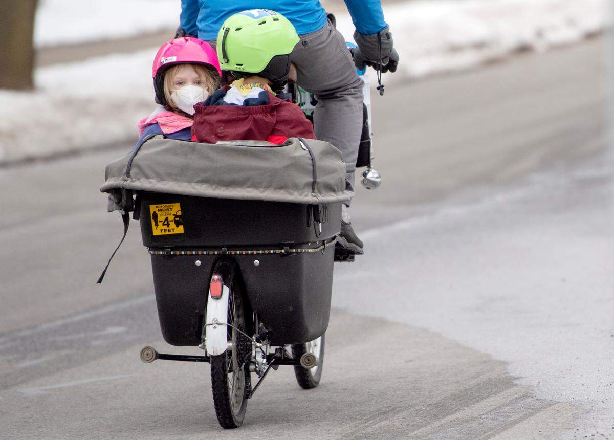 A sticker reminding cars to give bikers 4 feet of space on the back of Matt Herndon’s bike as he rides him from school with his kids, Fern and Rolin, on Feb. 2.