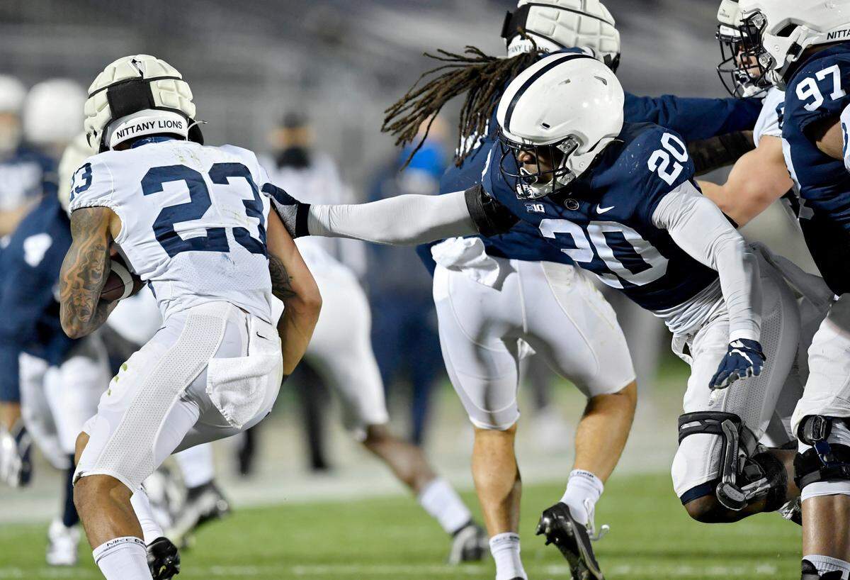Penn State defensive end Adisa Isaac reaches for running back John Lovett during Penn State football practice on Friday, April 23, 2021 at Beaver Stadium.